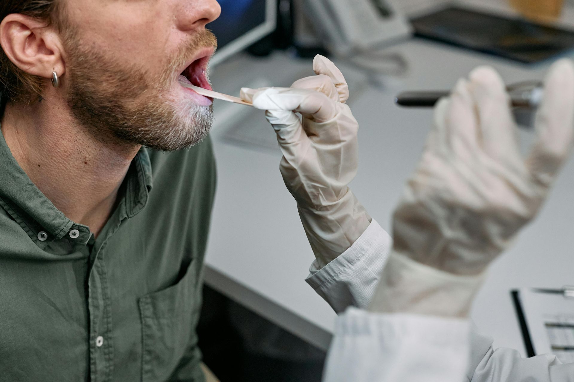 A patient in Dearborn, MI, getting his throat checked by a doctor at MedCare Urgent Care.
