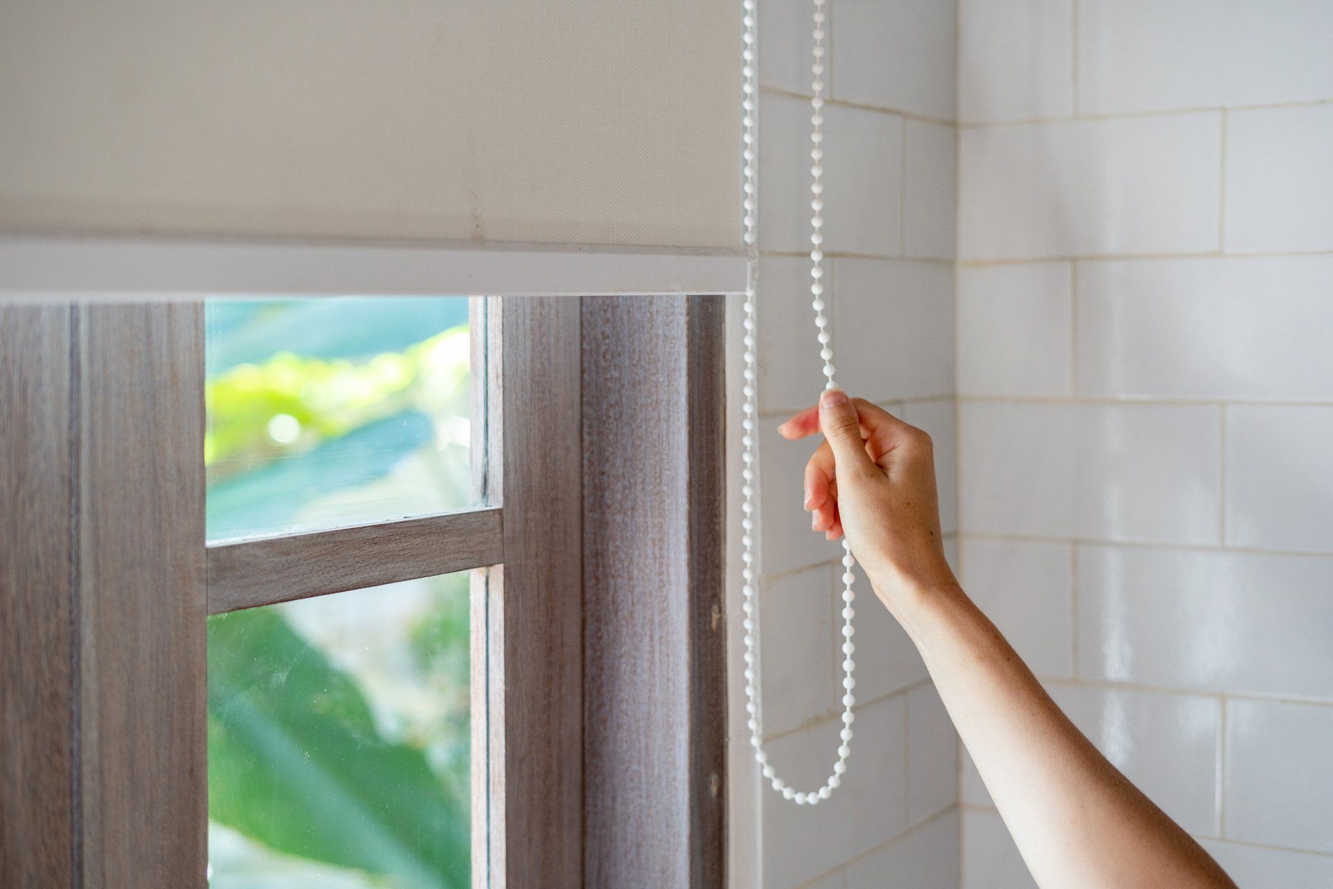 hand operating all-white roller shades