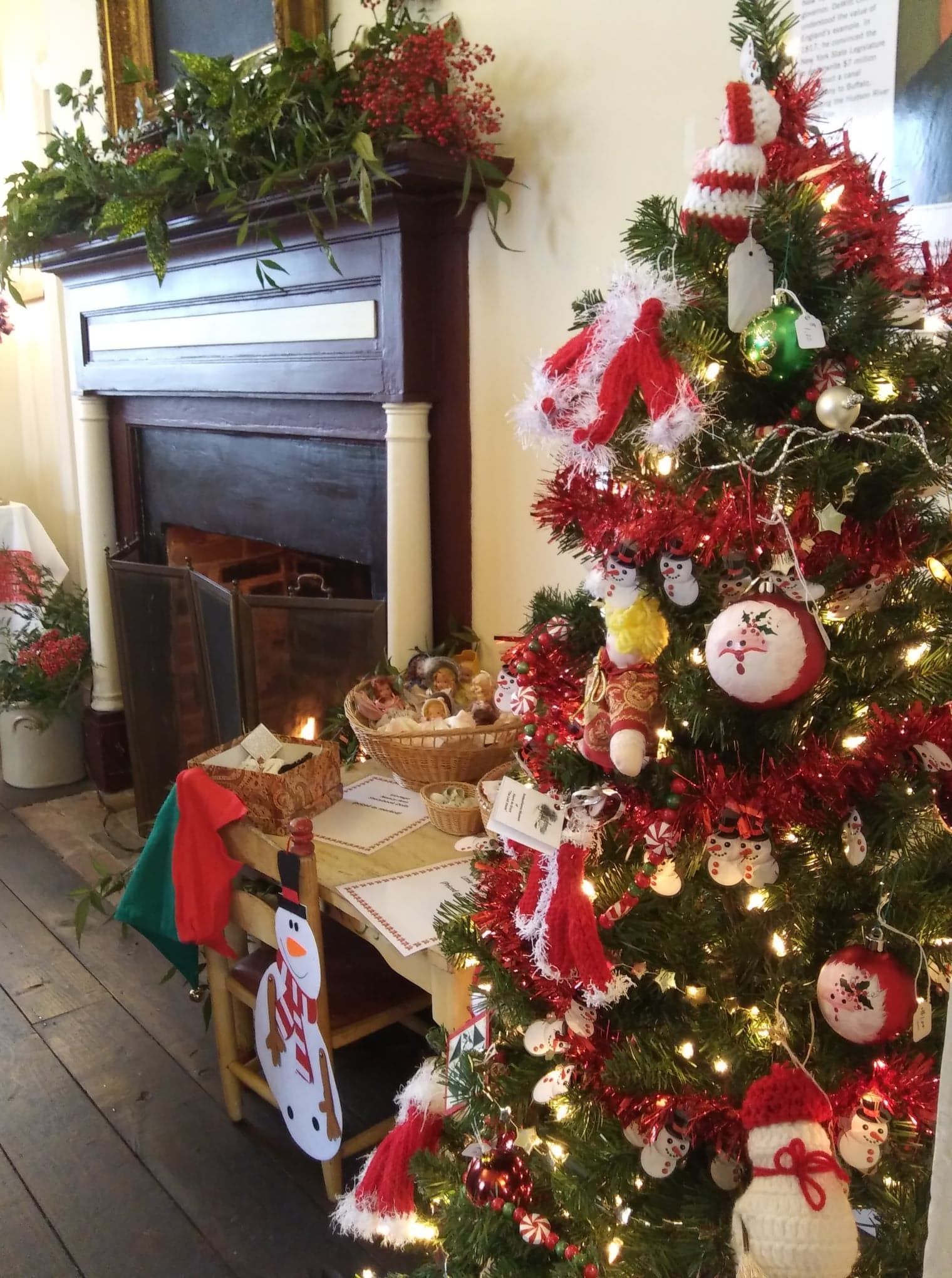 Christmas tree decorated with red and white ornaments next to a fireplace.