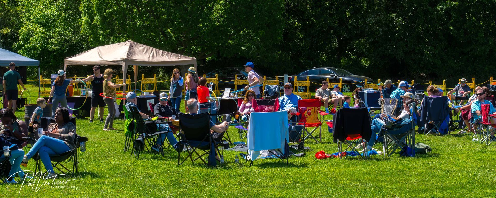 A group of people enjoying an outdoor event on a grassy field on a sunny day.