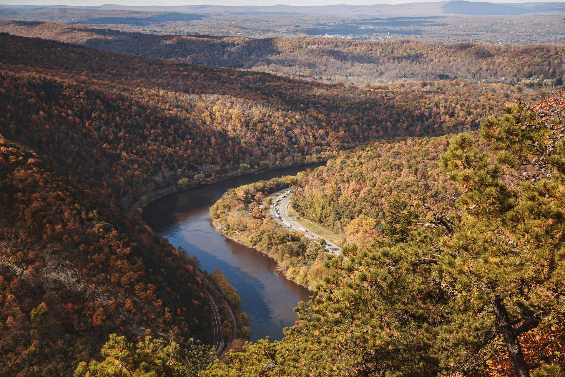 River winds through a valley with autumn foliage. Highway follows the river.