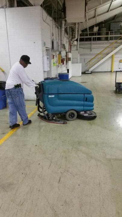 A man is cleaning the floor of a building with a machine.