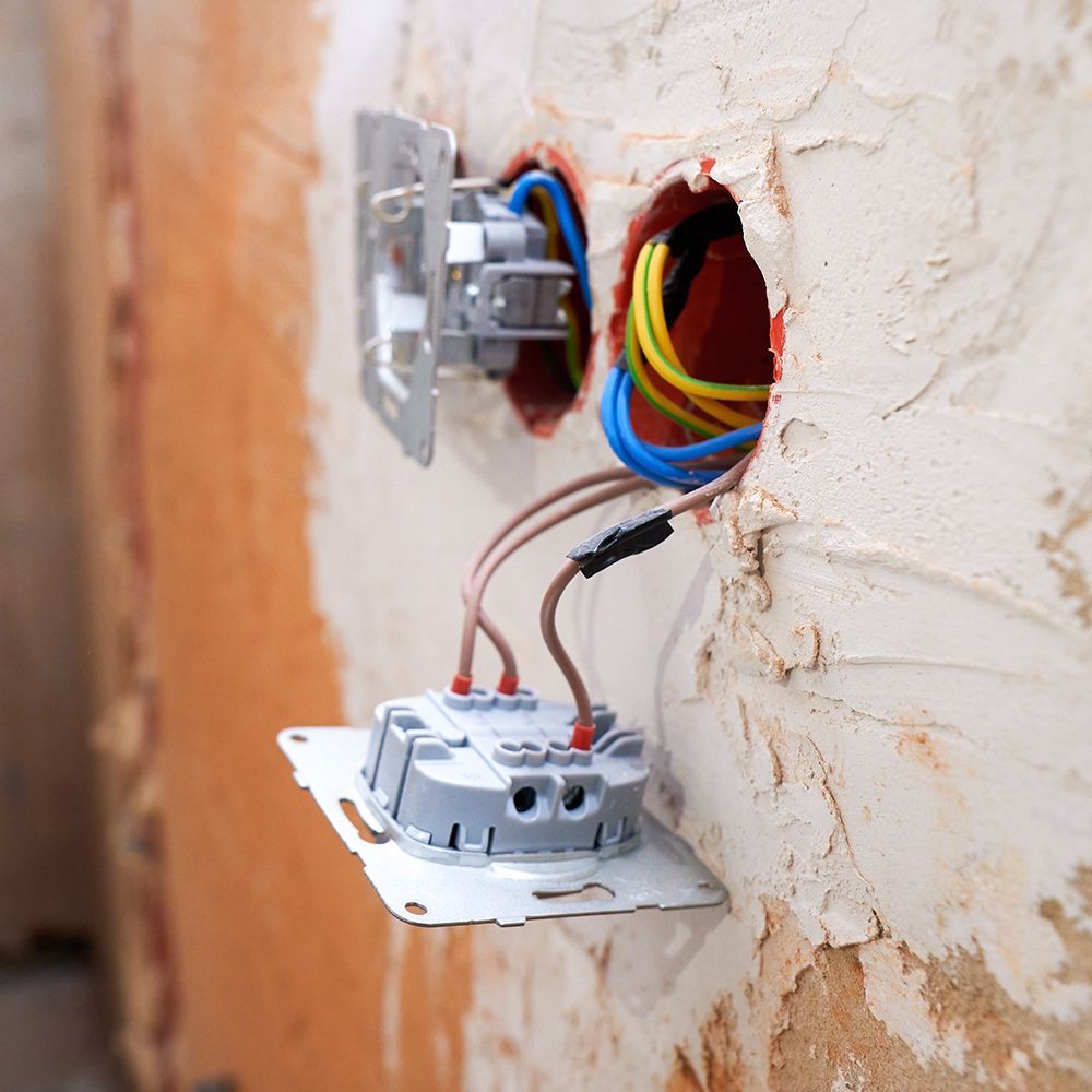 Two electrical switches are being installed in a brick wall.