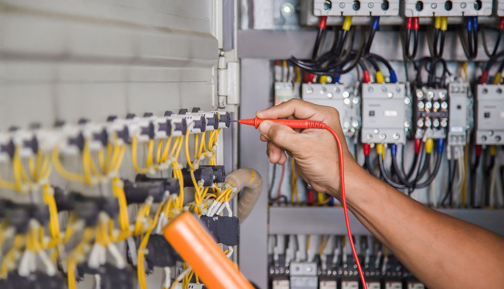 An electrician is using a multimeter to test a circuit board.