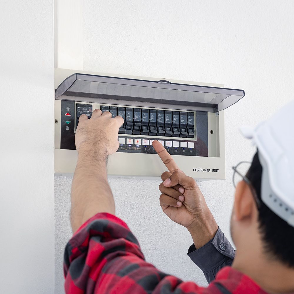 A man in a plaid shirt is working on an electrical box