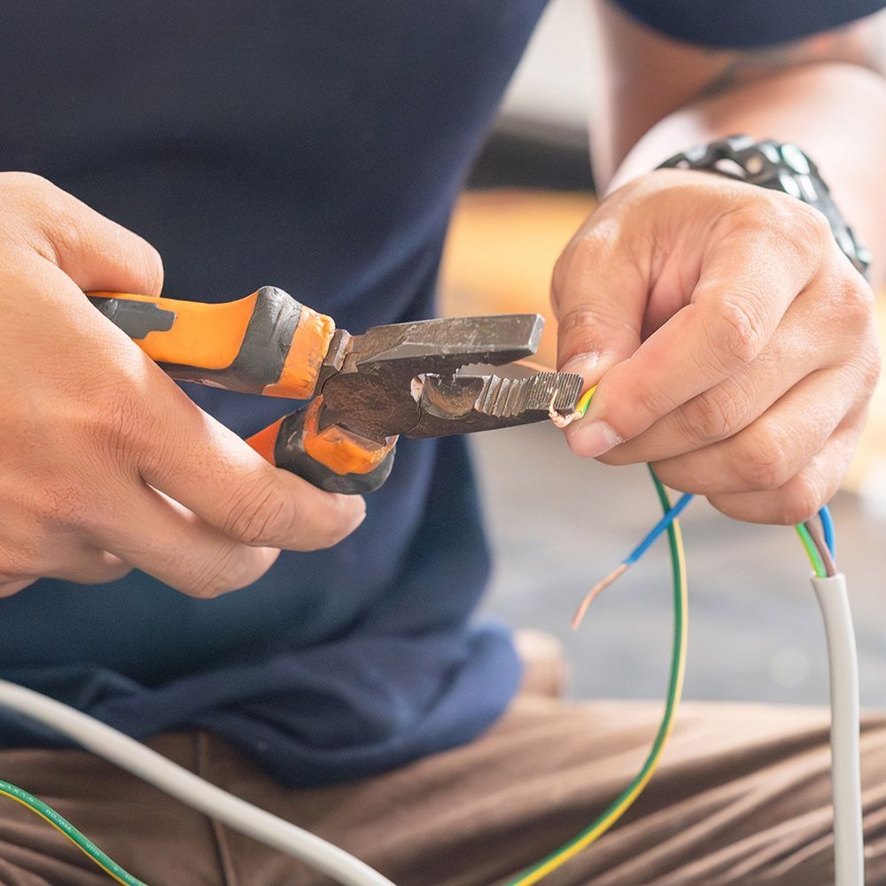 A man is cutting a wire with a pair of pliers.