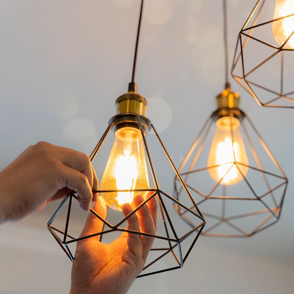 A person is holding a light bulb in a diamond shaped cage