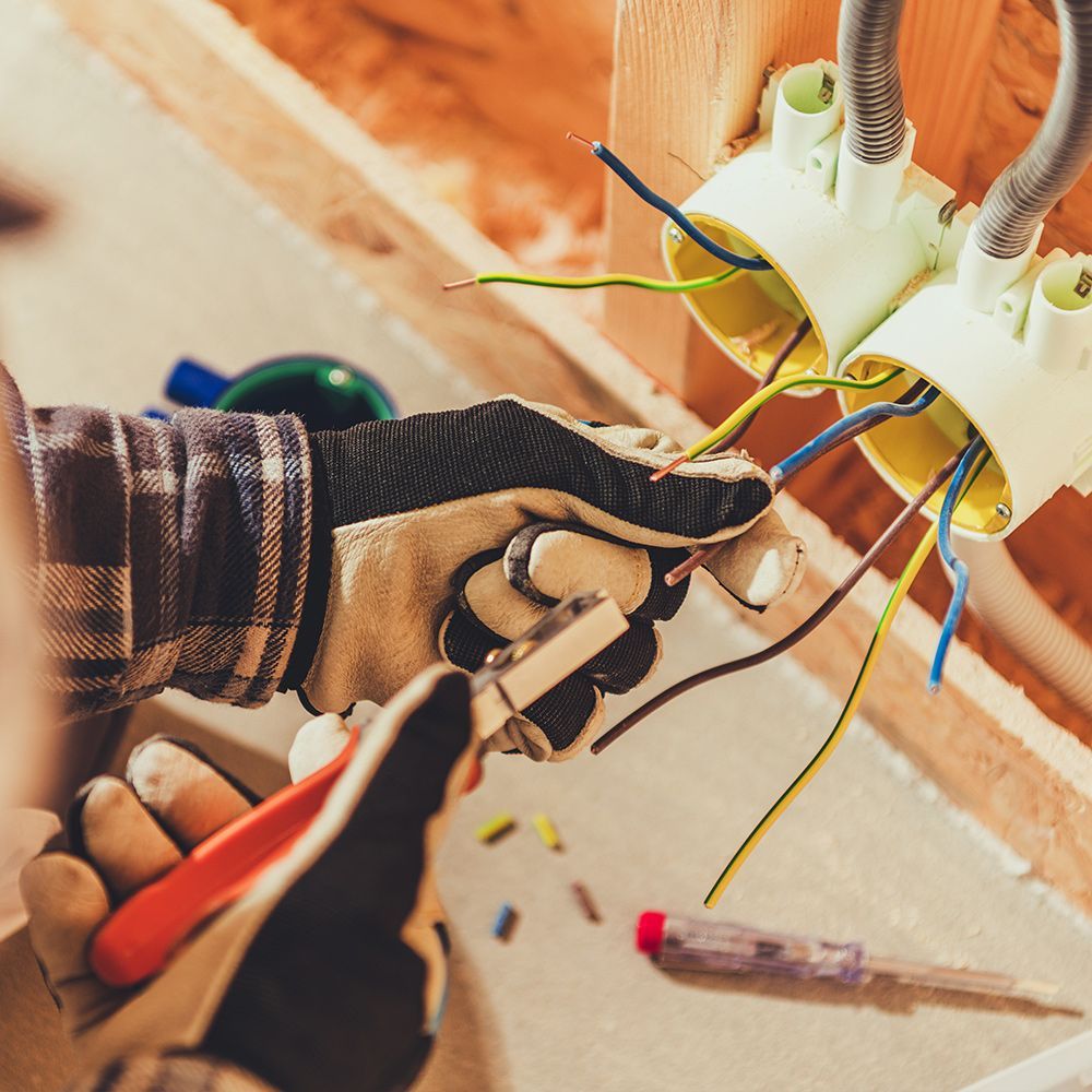 A person wearing gloves is working on electrical wires