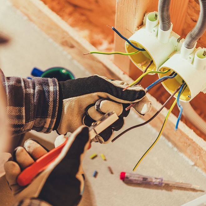A person wearing gloves is working on electrical wires