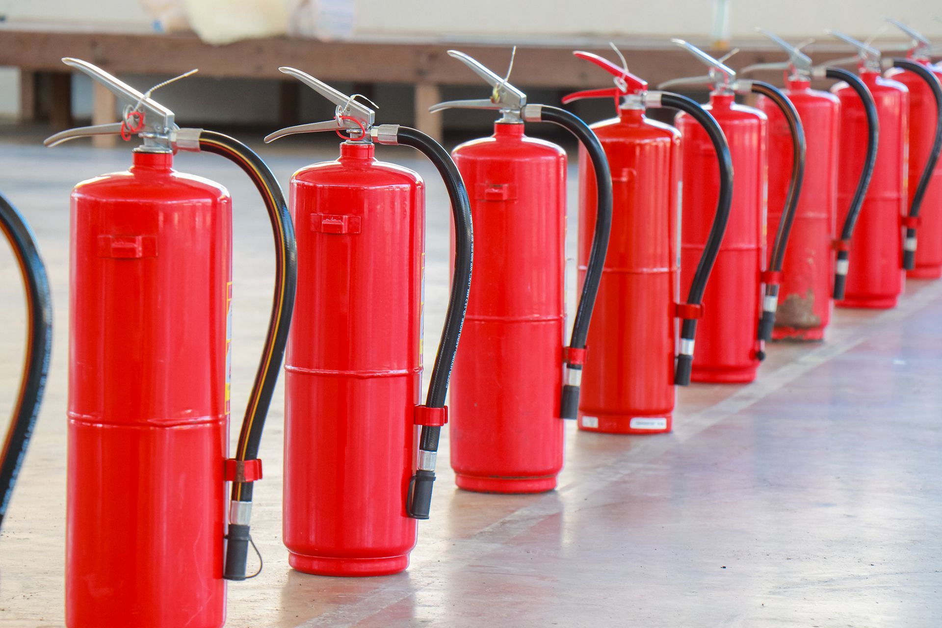 Row of red fire extinguishers lined up on a smooth floor. Row of red fire extinguishers lined up on a smooth floor.