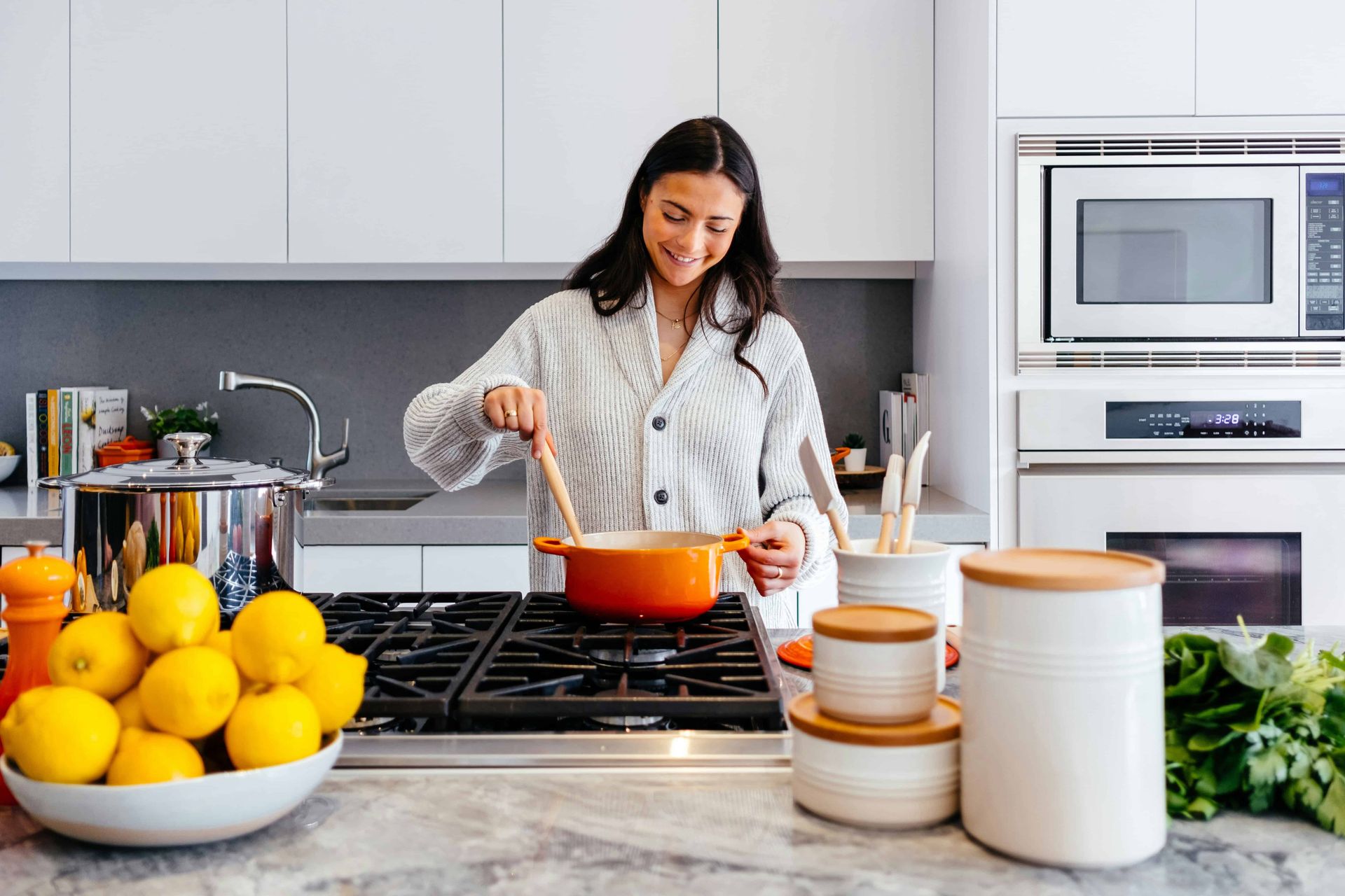A lady cooking in front of a nice kitchen sink 