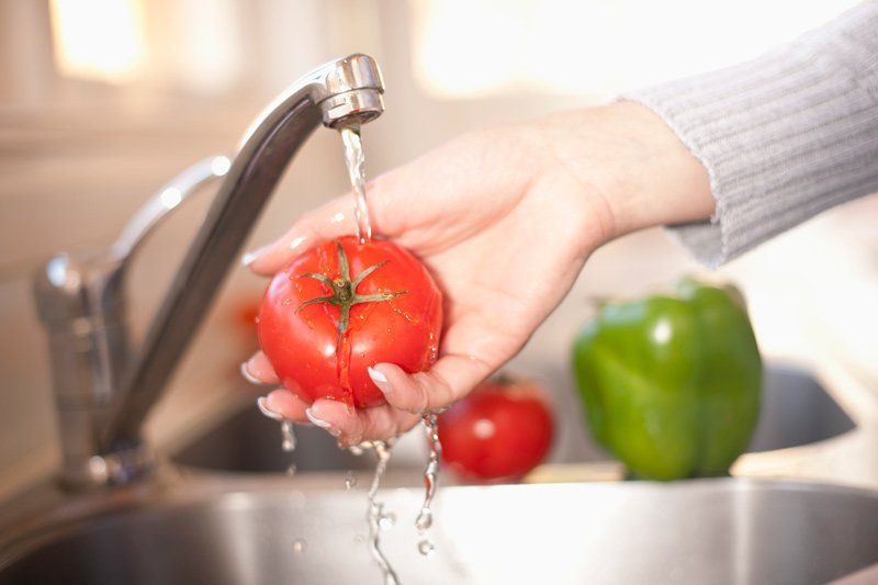 Vegetables being cleaned in a well-maintained sink by filtered tap water. 