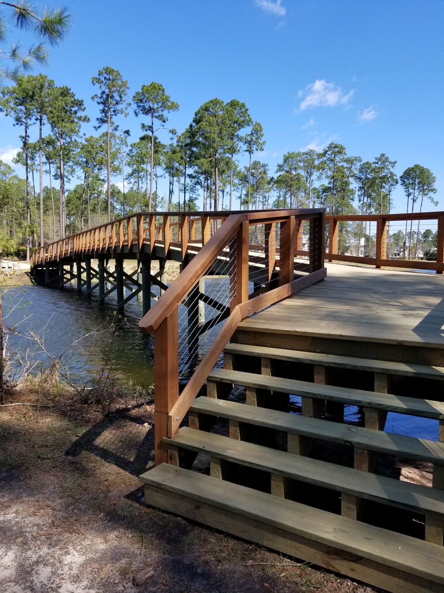 A wooden bridge over a body of water with stairs leading to it.