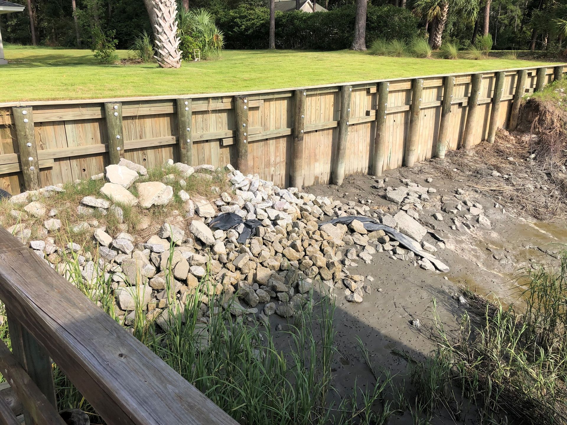 A wooden fence is surrounded by rocks and grass.