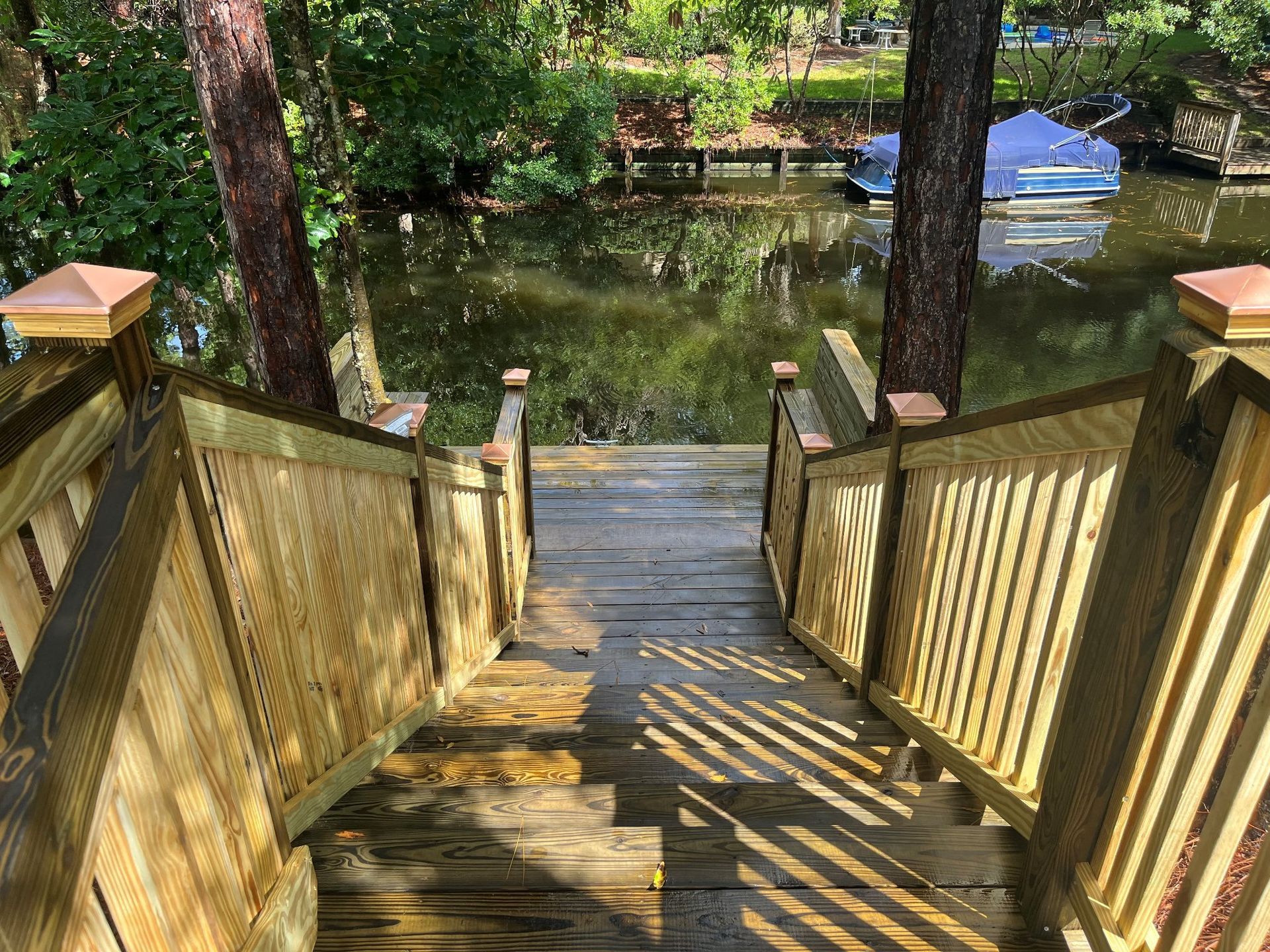 A wooden deck with stairs leading up to a lake.