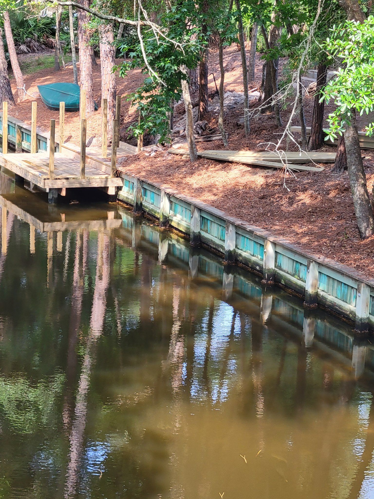 A boat is docked on a dock next to a body of water surrounded by trees.