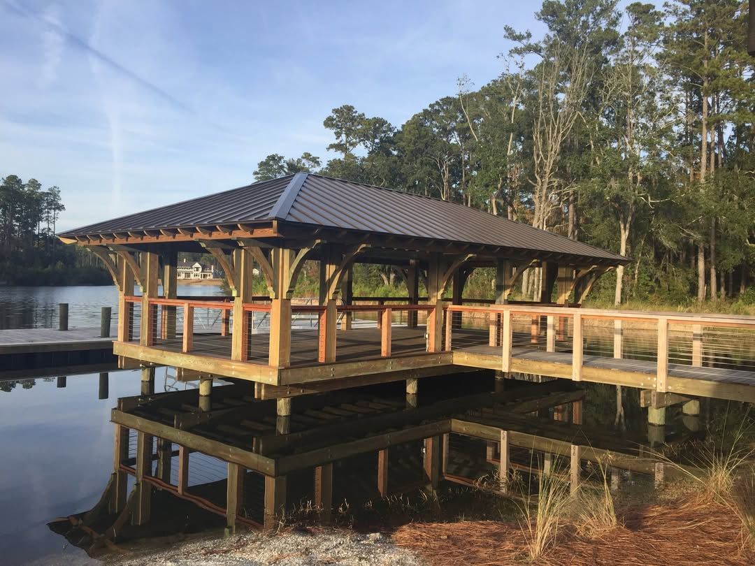 A wooden pavilion is sitting next to a body of water.