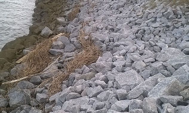 A pile of rocks on the shore of a body of water.