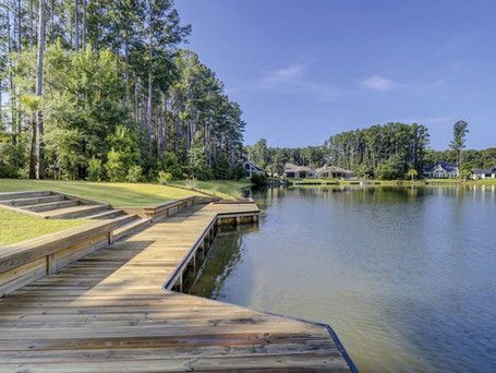 A wooden dock leading to a lake with trees in the background.