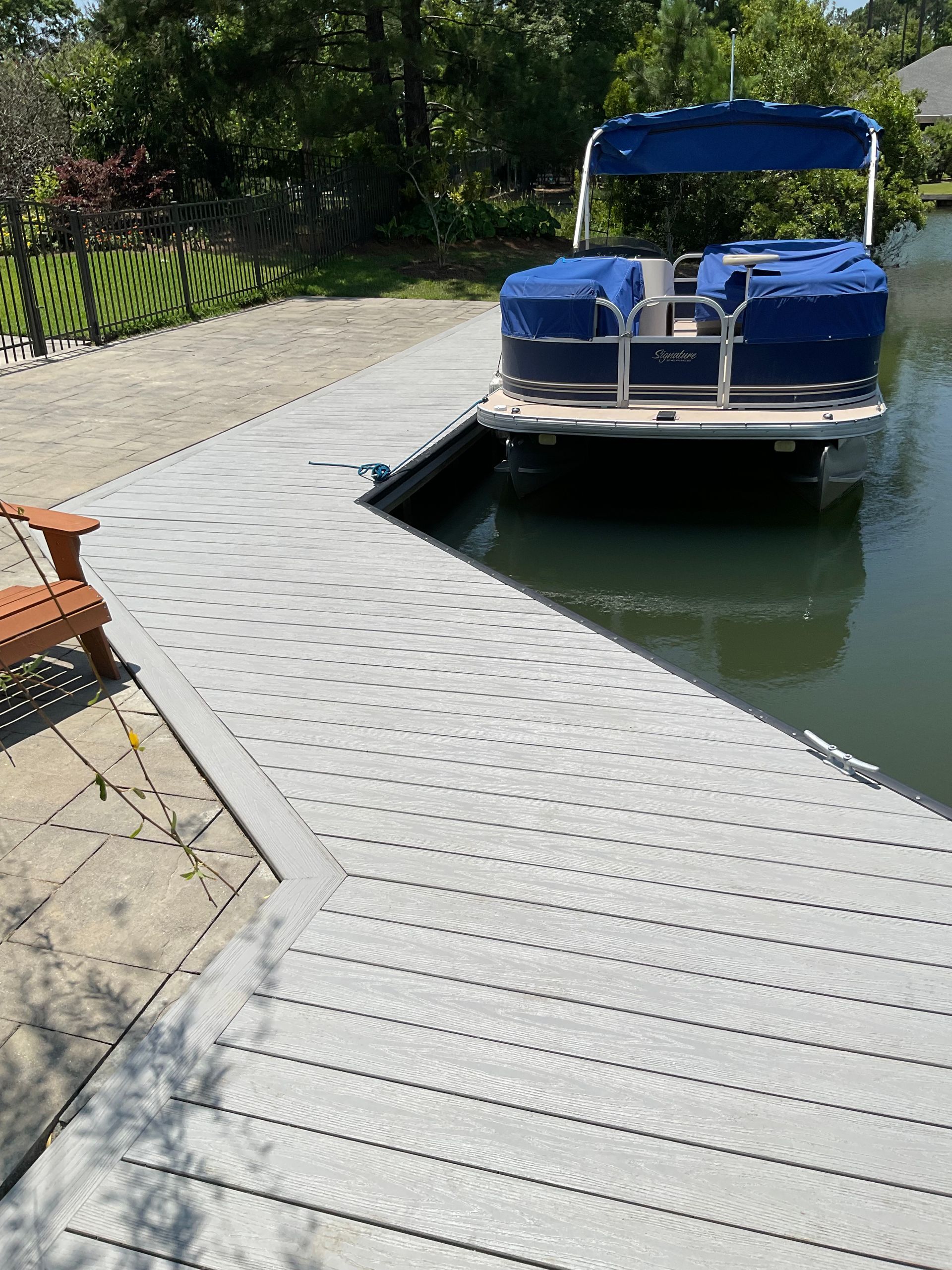 A pontoon boat is docked at a dock on a lake.