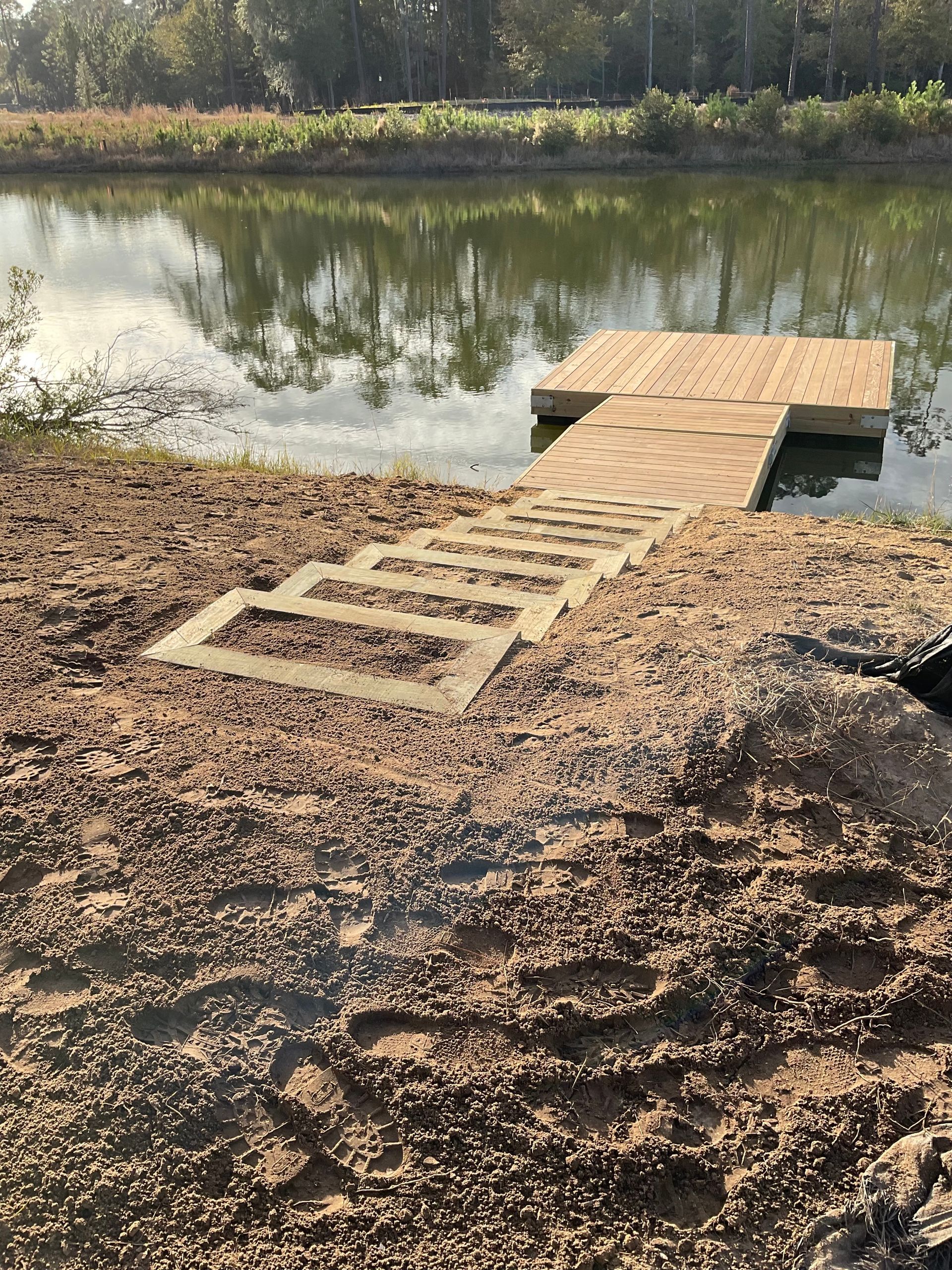 A dog is standing next to a wooden dock next to a lake.