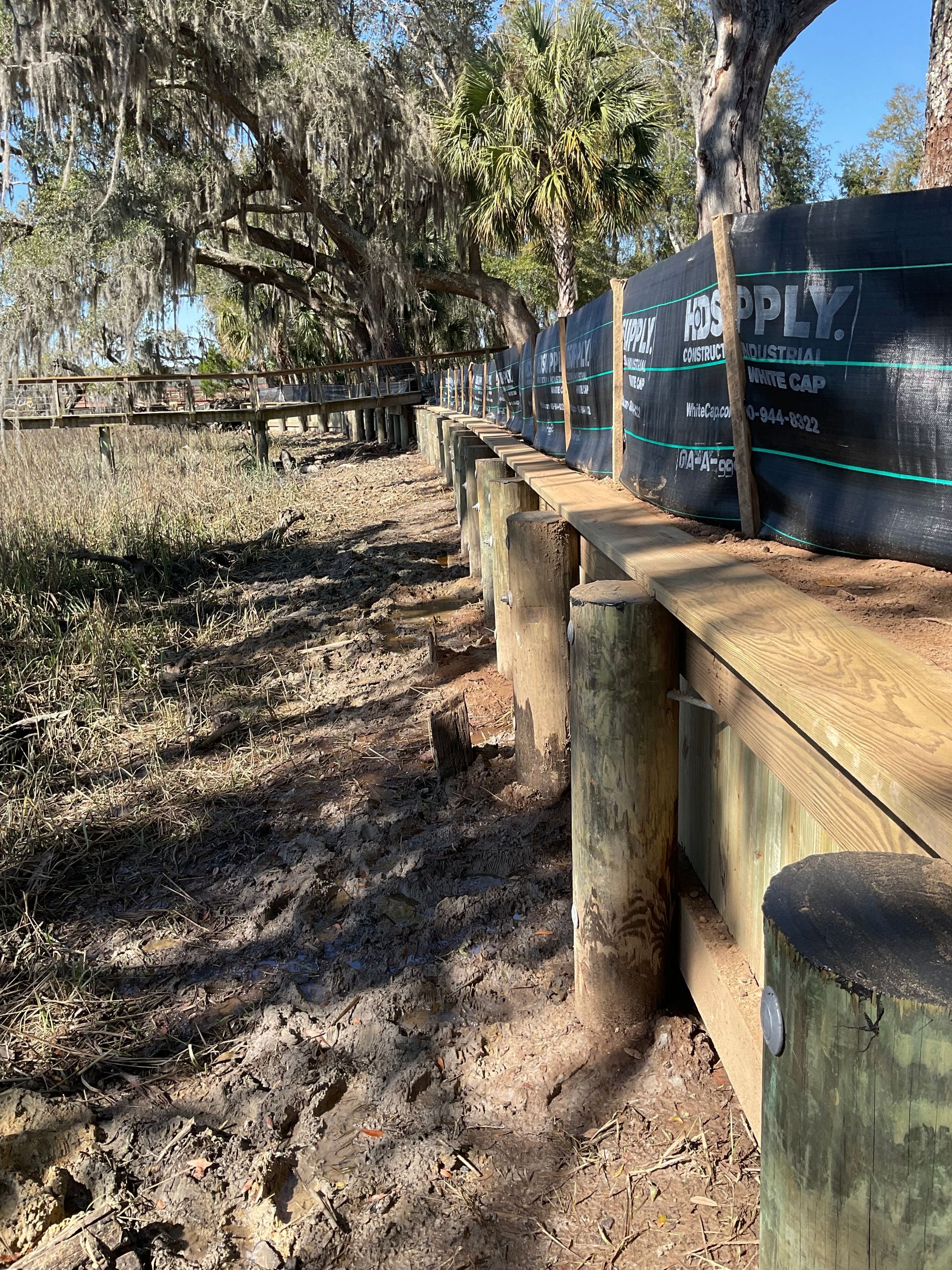 A row of wooden posts sitting on top of a dirt field.