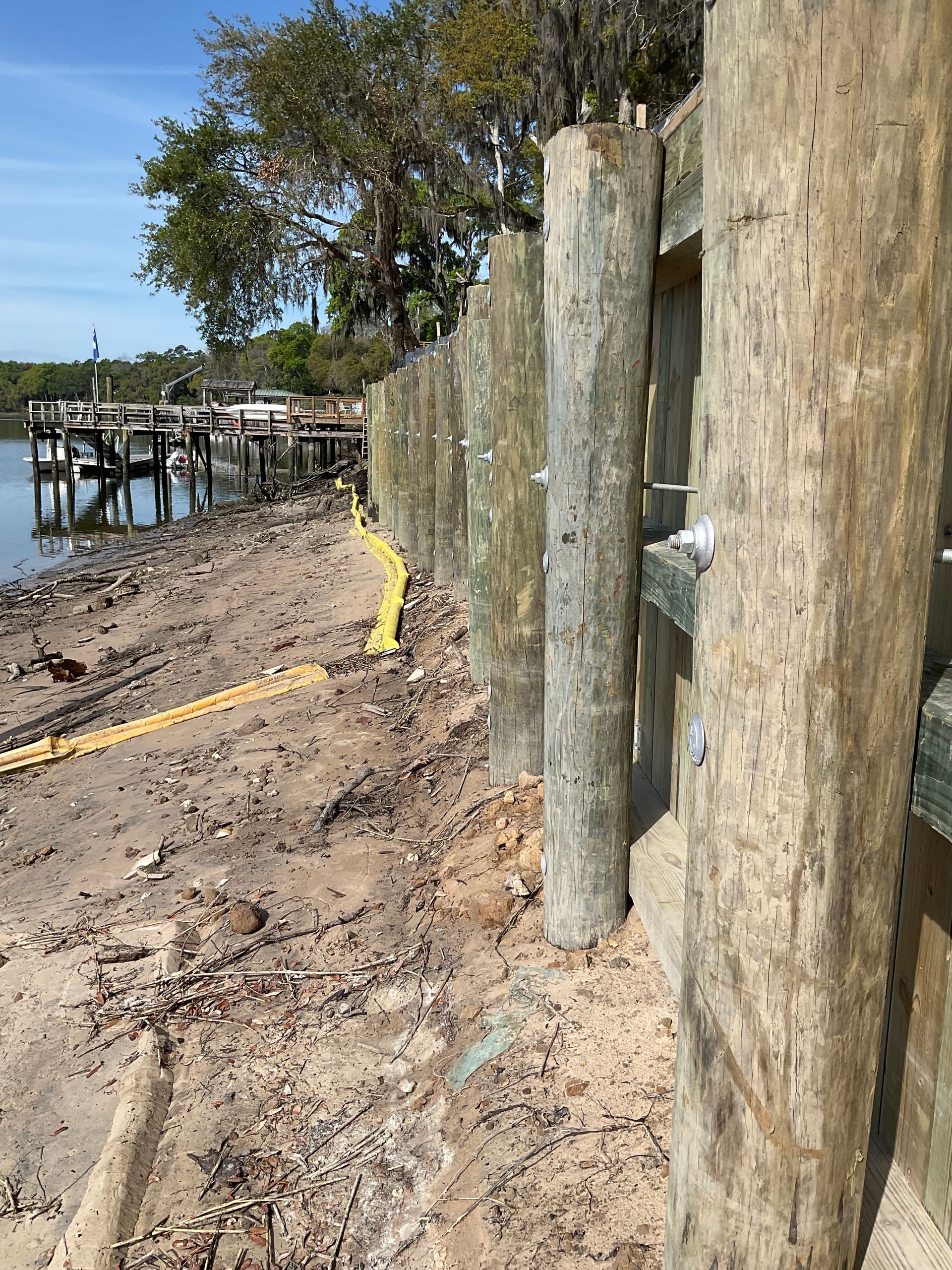 A wooden fence is being built on a beach next to a body of water.