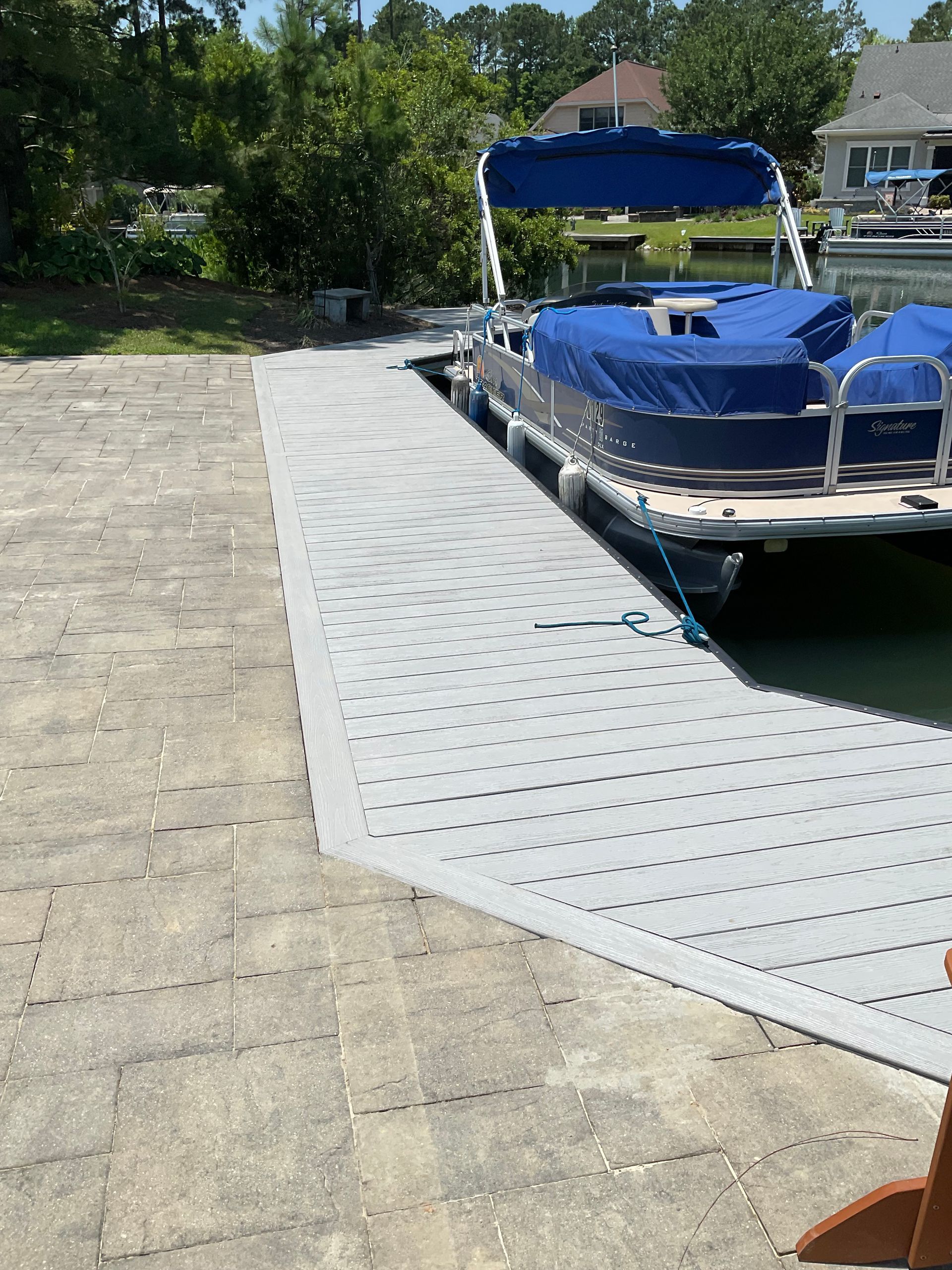 A blue pontoon boat is docked at a dock