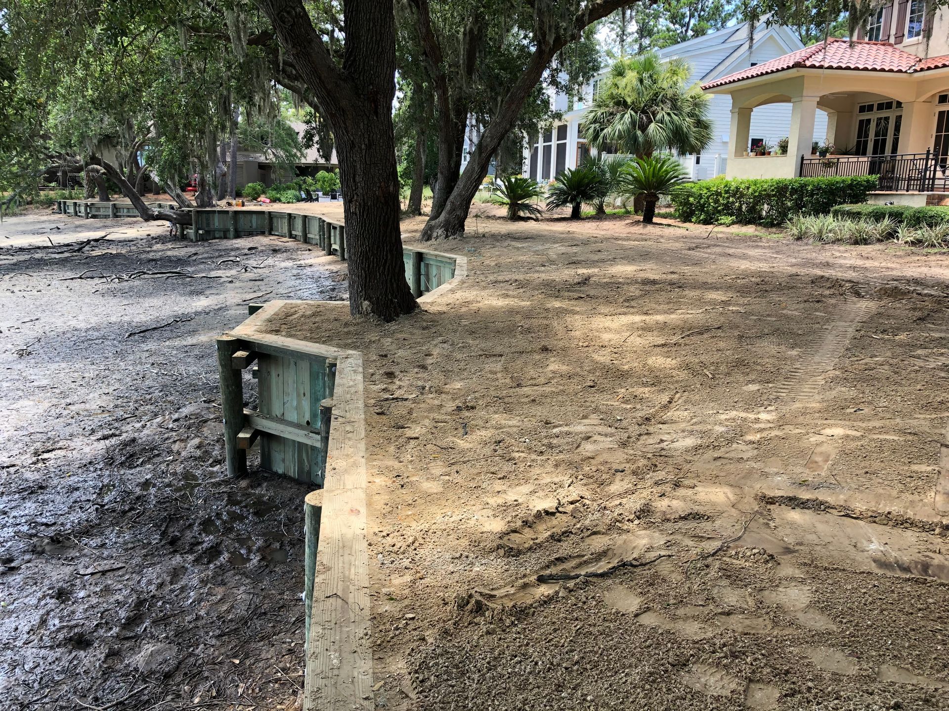 A flooded yard with a house in the background and a tree in the foreground.