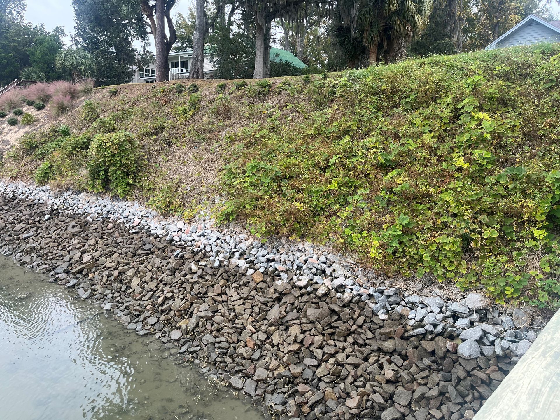 A rocky hillside next to a body of water with trees in the background.