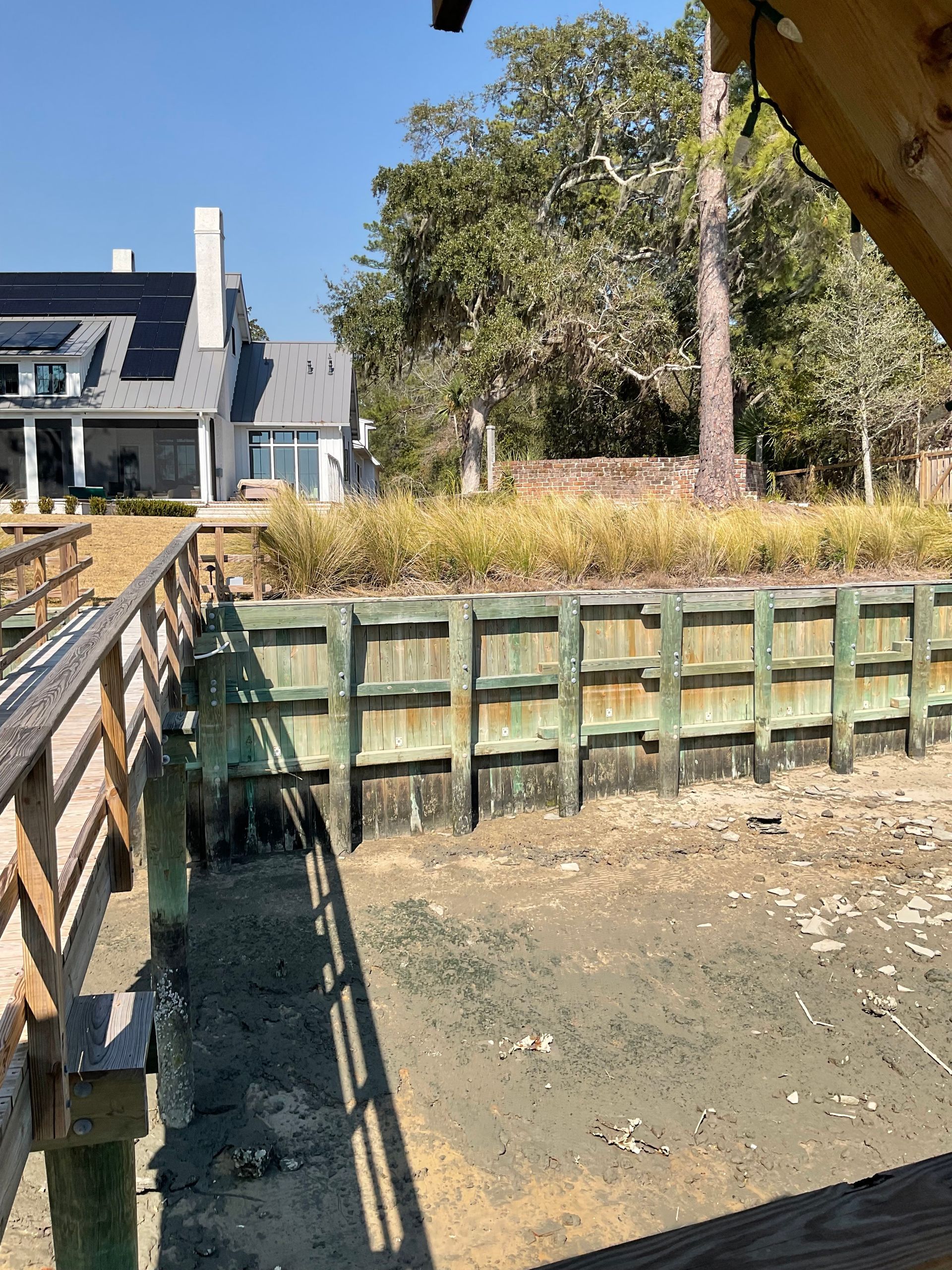 A wooden bridge over a body of water with a house in the background.