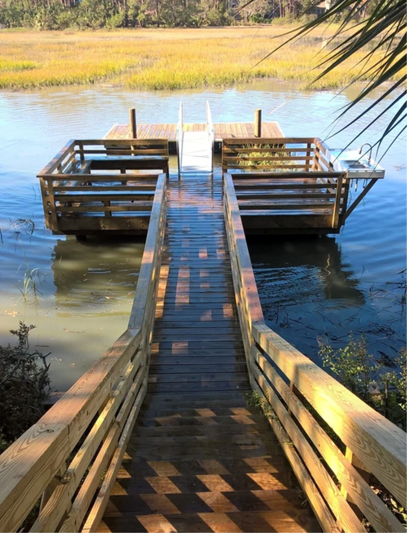 A wooden bridge leading to a dock in the middle of a body of water.