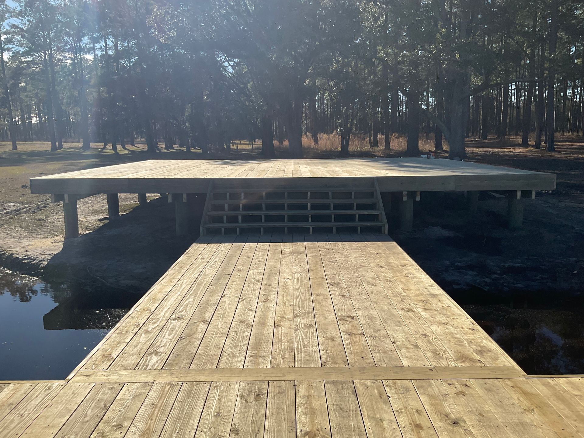 A wooden pavilion is sitting next to a body of water.