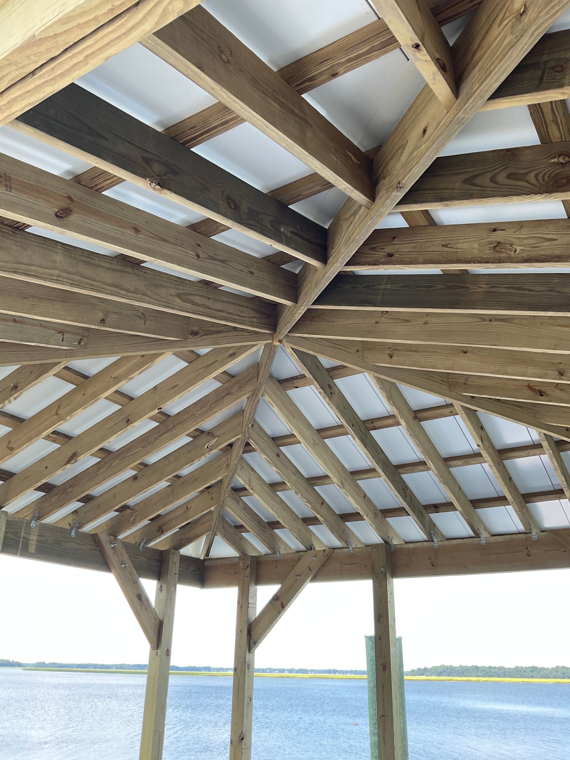 A wooden structure with a roof overlooking a body of water.
