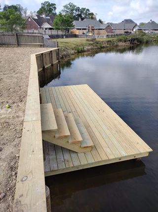 A wooden dock is sitting next to a body of water.