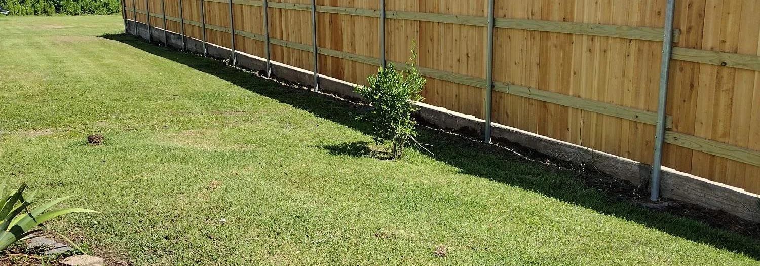 A wooden picket fence with a gate in front of a brick house.