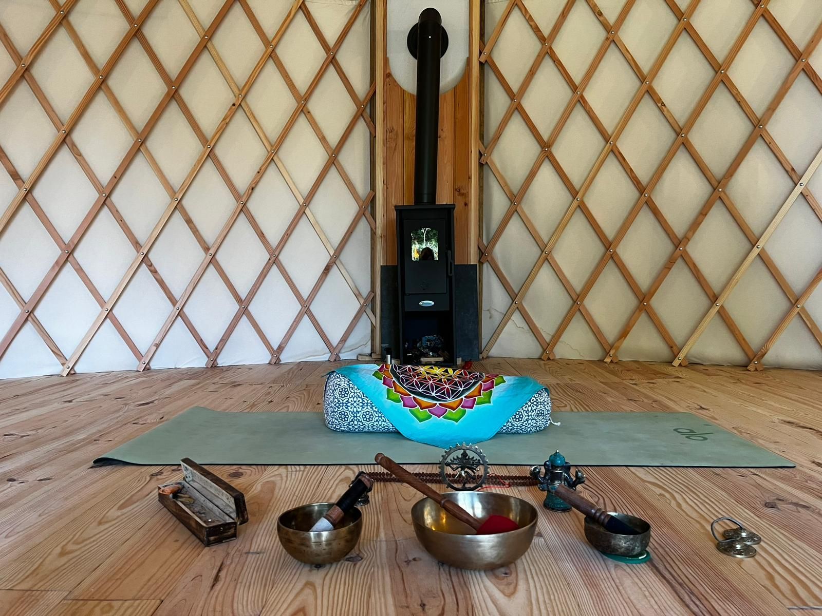 Intérieur d'une yourte avec tapis de yoga, outils de méditation et poêle à bois.