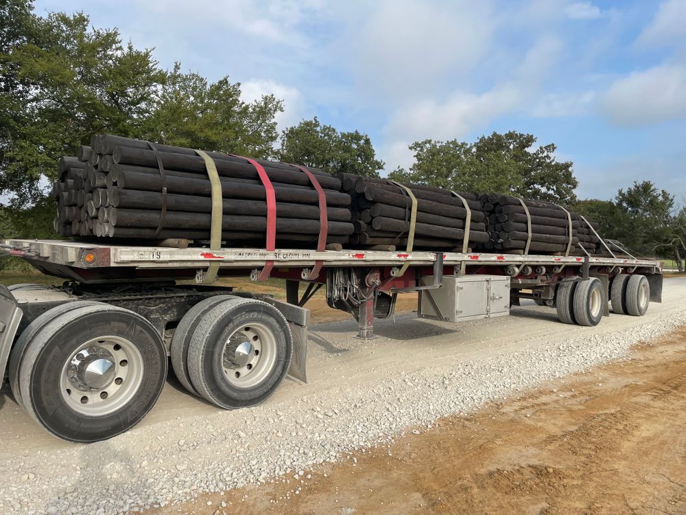 A semi truck is carrying a load of logs on a gravel road.