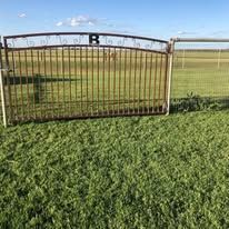 A metal gate is sitting in the middle of a grassy field.