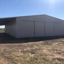 A large white building is sitting in the middle of a field.