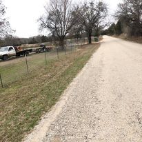 A truck is towing a trailer down a dirt road.