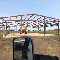 A truck is parked in front of a large metal structure under construction.