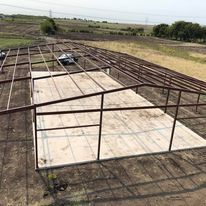 An aerial view of a metal structure being built on top of a dirt field.