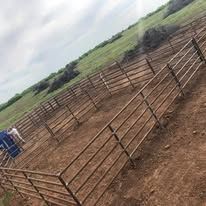 A large metal fence surrounds a dirt field.