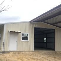 A large metal building with a large garage door and a window.