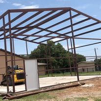 A large metal structure is being built next to a house.