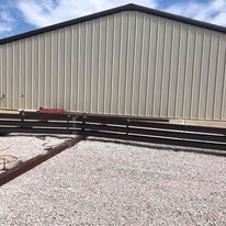 A large metal building with a wooden fence in front of it.
