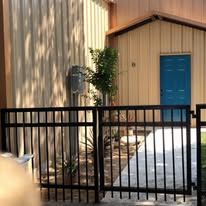 A metal fence surrounds a building with a blue door.
