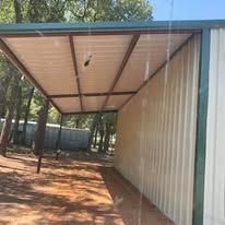 A carport with a roof that is open and a fence in the background.