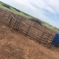A row of wooden fences surrounding a dirt field.